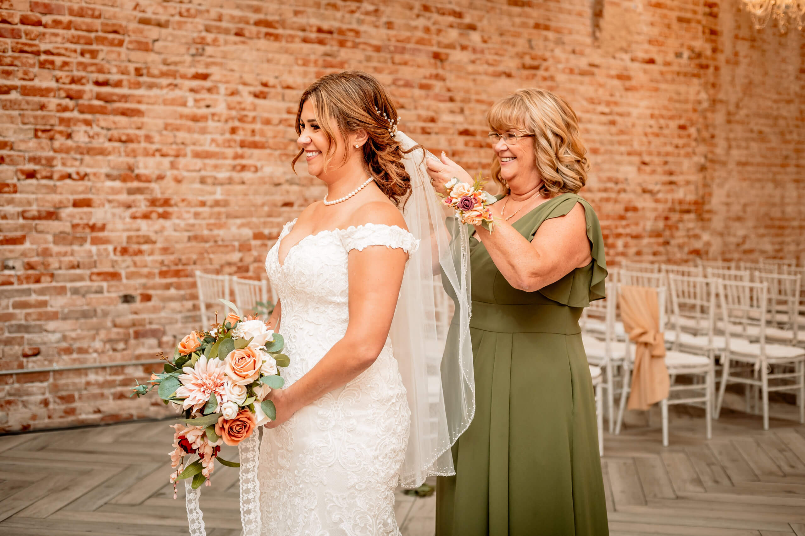 photo of mom fixing bride's veil with red brick wall at Tri Bella