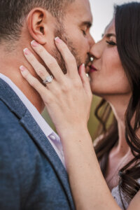 Close up intimate photo of couple kissing but focus on the wedding ring and hand.