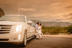 photo of eloped couple kissing at limo with the mountains in the background