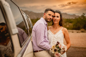 photo of elopement couple leaned up against limo looking into camera