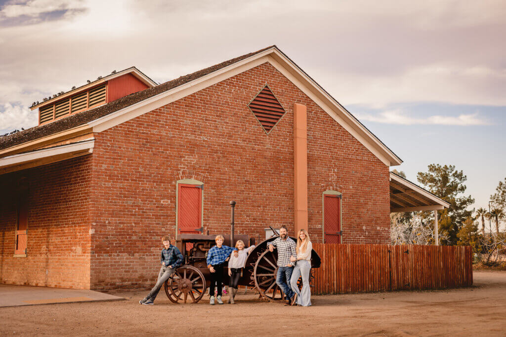 family photo in front of brick barn at Sahuaro Ranch Park in Glendale, AZ