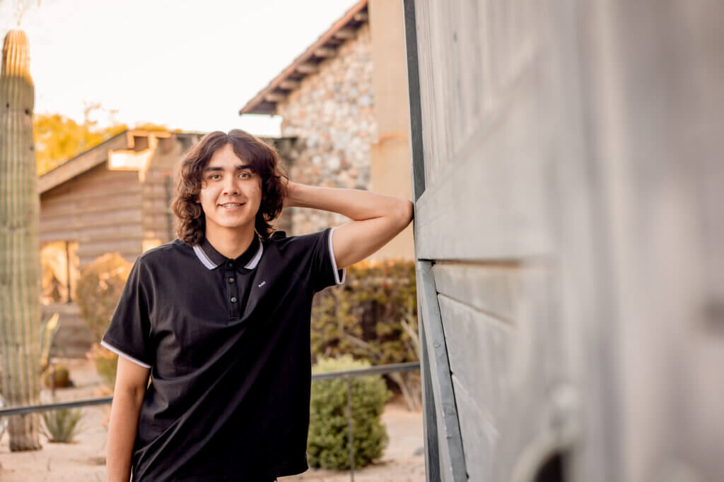 senior portraits leaning up on wall of barn door