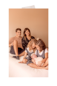 In-home Family photo with parents looking at their children in the background and newborn baby with siblings by Phoenix Photographer Memories by Candace