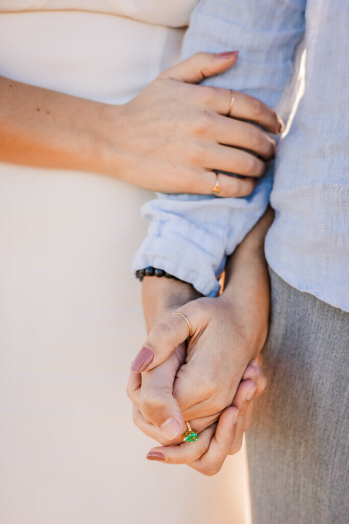 Photo of engagement ring on hand and couple holding hands