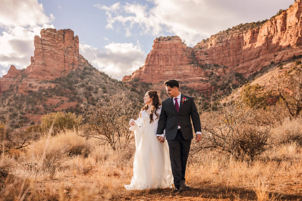 Photo of bride and groom walking with the Sedona Red Rocks in the background
