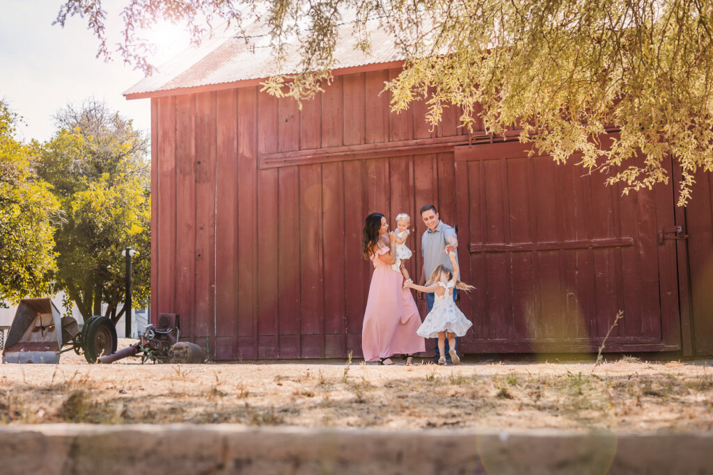 Phoenix family interacting with big red barn as background at Glendale photography location.