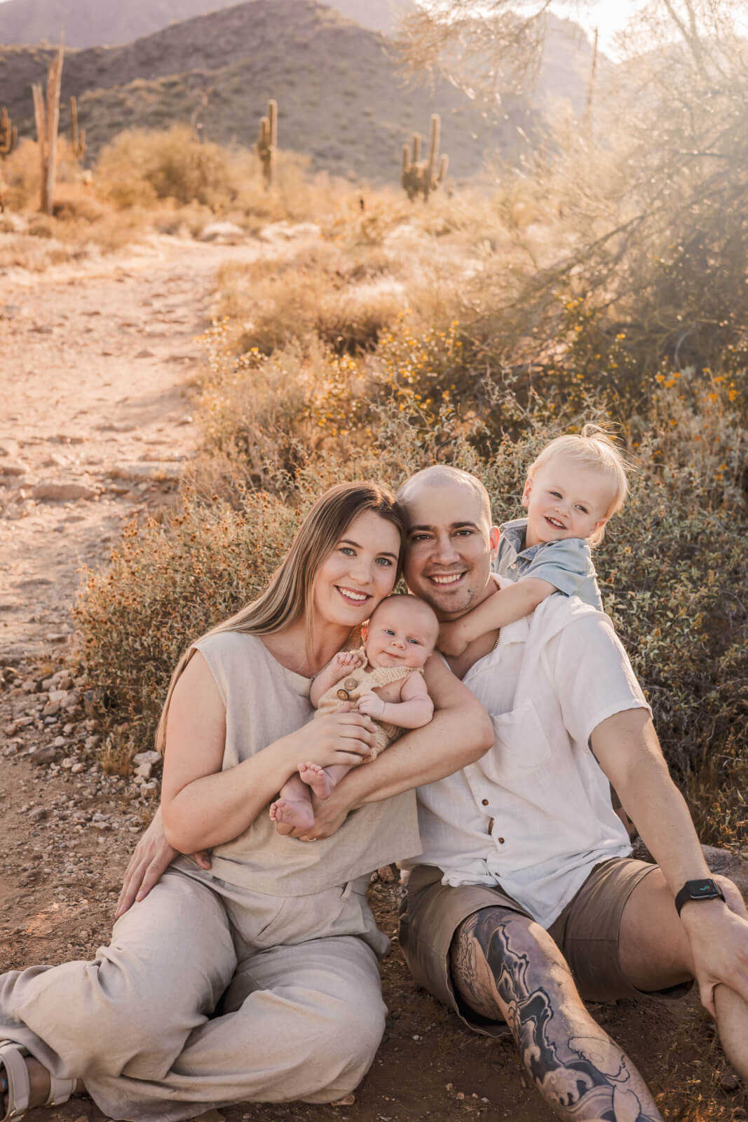 Parents smiling with their newborn and toddler in the Arizona desert.
