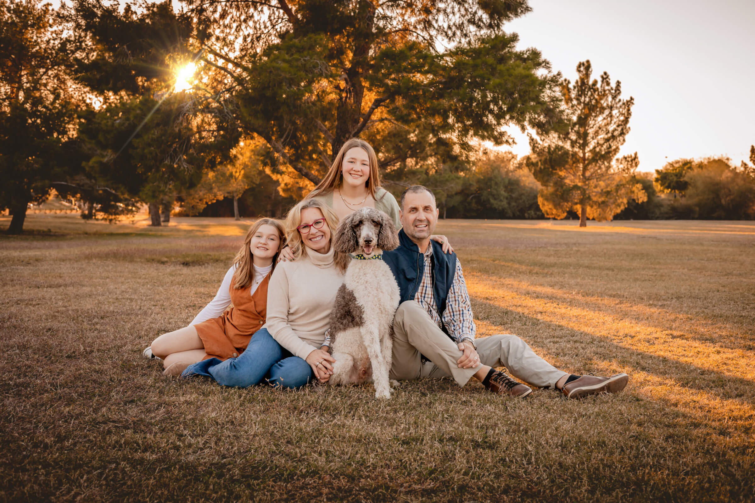 Family photo posed with dog, Poodle Winston, at green location in Phoenix, AZ.
