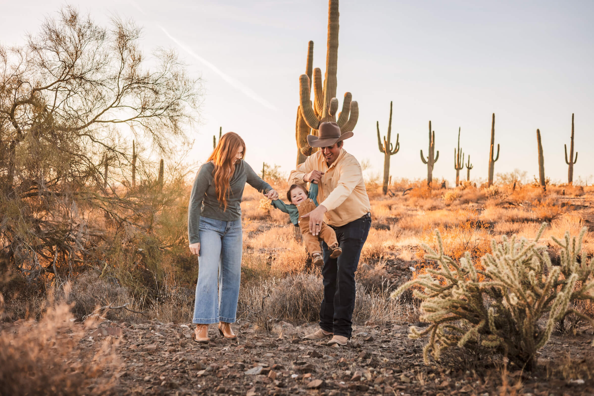Candid sweet moments of family playing with child in the Phoenix desert for photos.