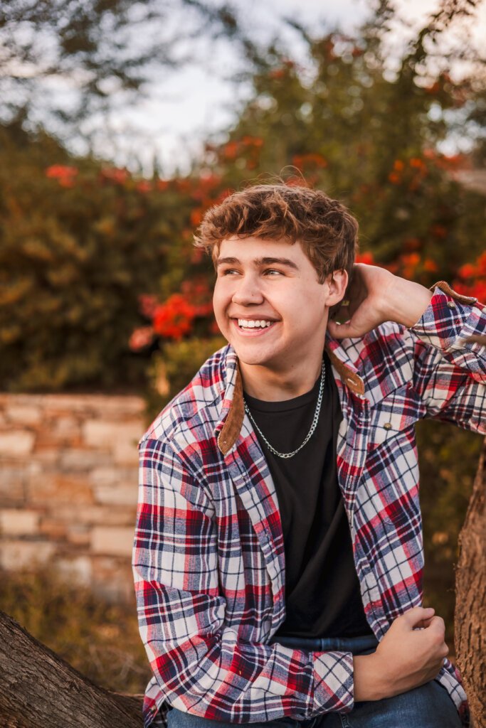 Close up photo of high school senior smiling with vibrant greenery in the background for Phoenix Senior Photos.