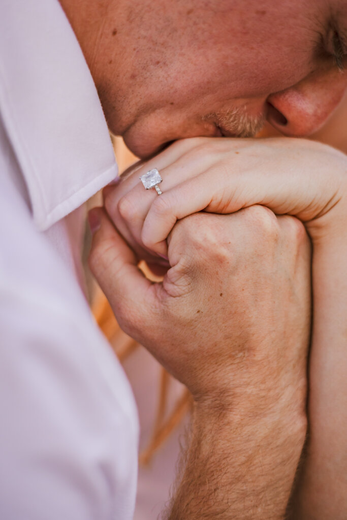 Close up photo of Caleb kissing Lauren's ring finger.
