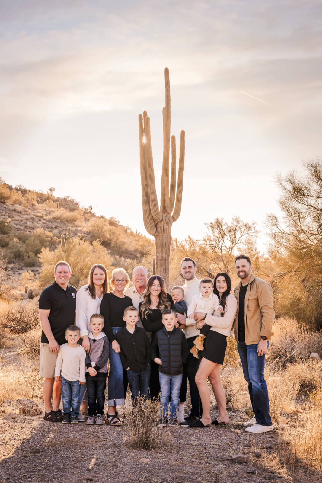 Large family session in the desert with mountains and cactus in the background.