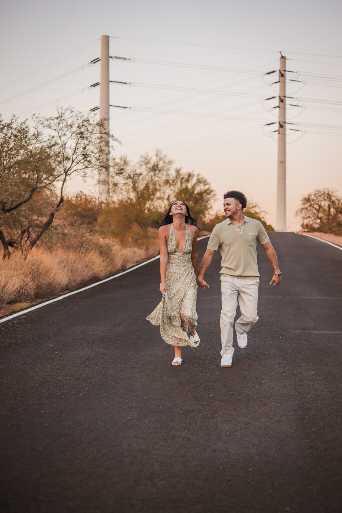 Couple skipping with one another in the road at Papago Park in Phoenix.