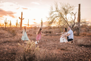 Summer family photoshoot with little girls running to mom and dad at sunset in the desert, captured by Phoenix photographer.