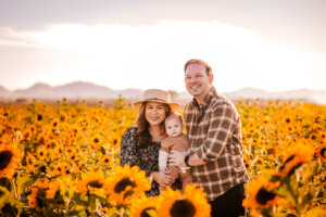 Fall family photo in sunflower fields with mountains in the background in Buckeye, AZ farm in October.