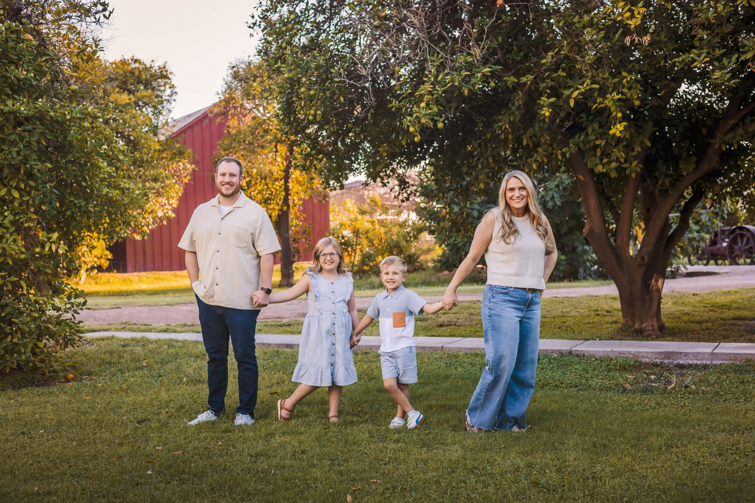 Family photo at green location in Phoenix, Arizona area with red barn and lush green trees in background.