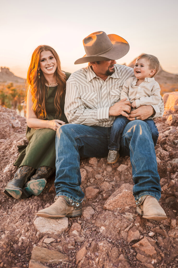 Candid Photo of family sitting on rocks with the Phoenix Papago Park Mountains in the background during golden hour sunset.