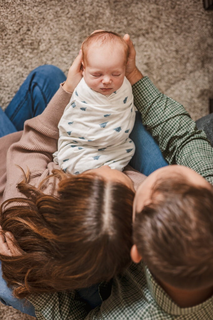 Photo of parents holding newborn in their arms for first baby newborn photos captured by Phoenix photographer.