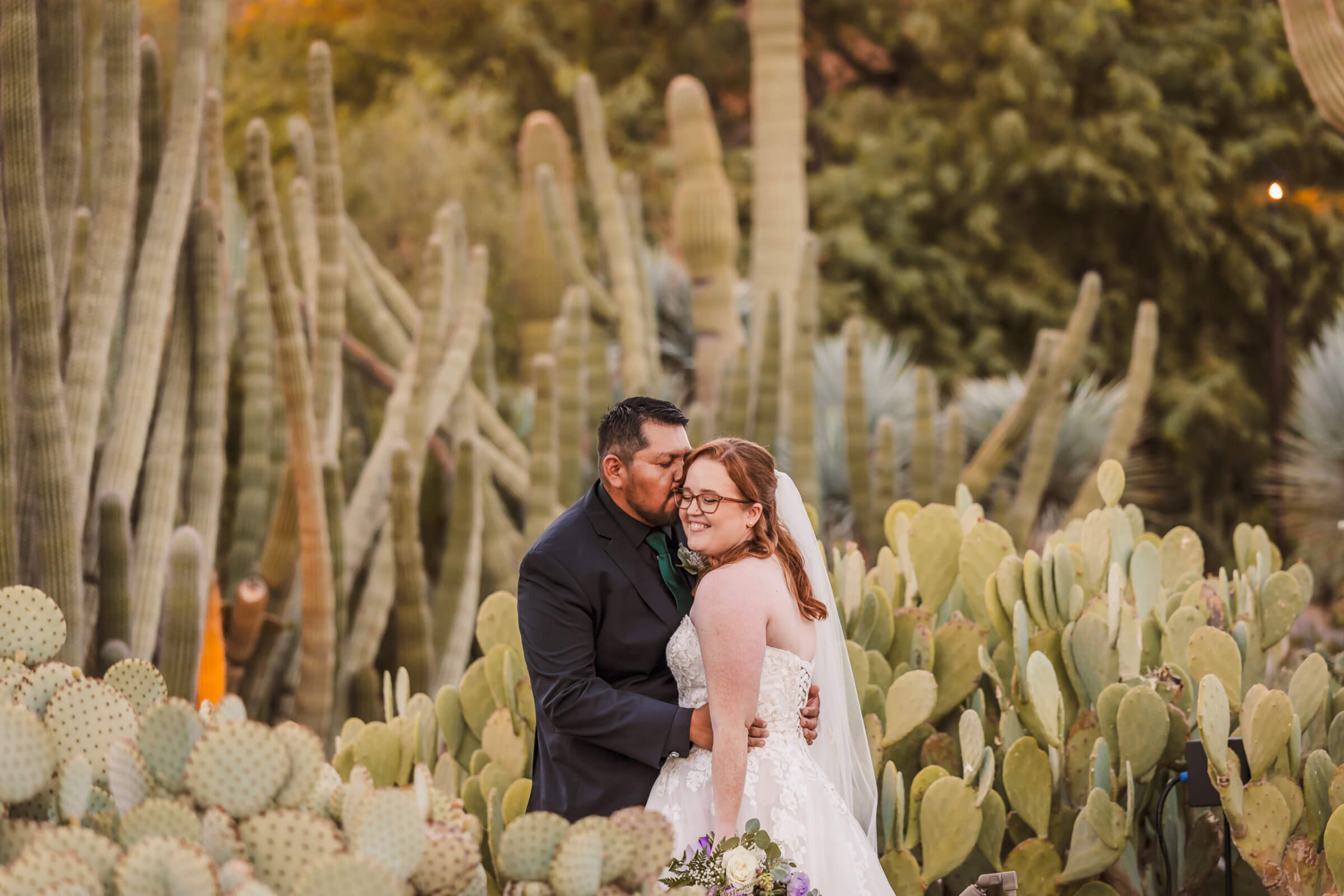 Couple embracing in the desert garden at sunset for wedding portraits.