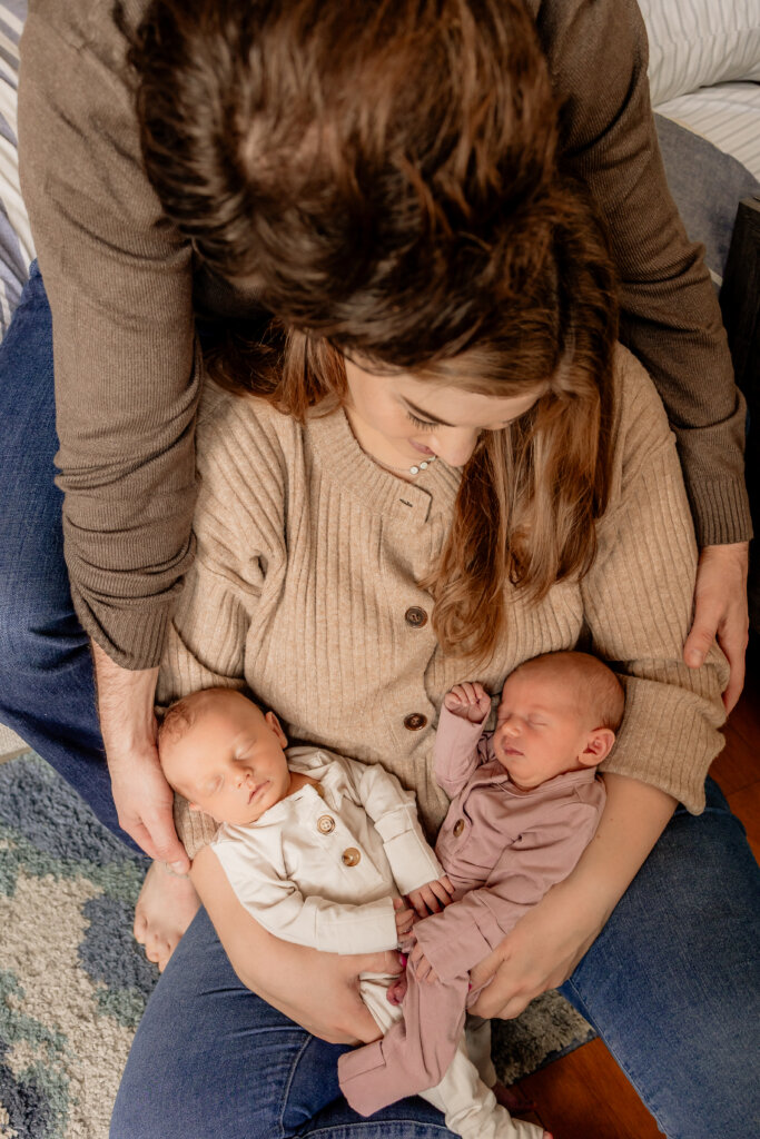 New parents holding their newborn twin girls during lifestyle session