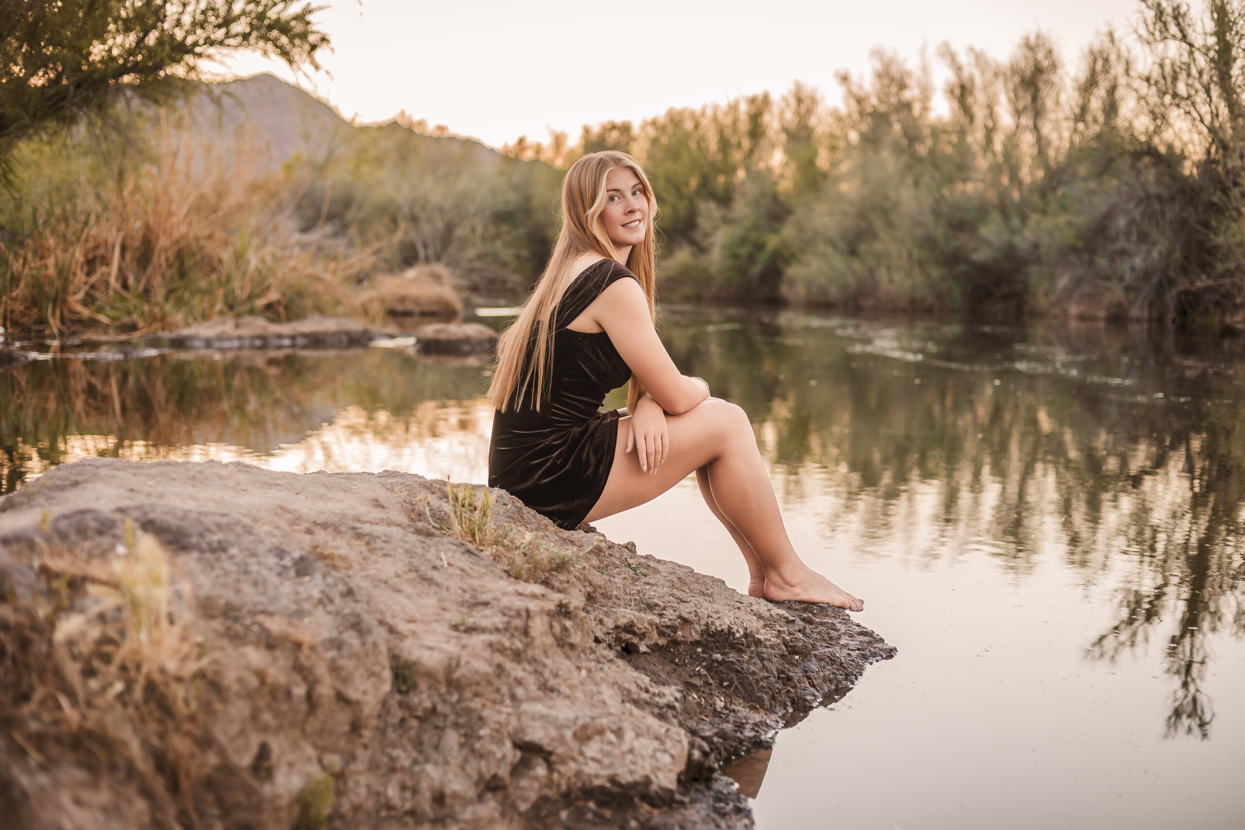 Senior portrait of girl sitting on riverbank of the Salt River.