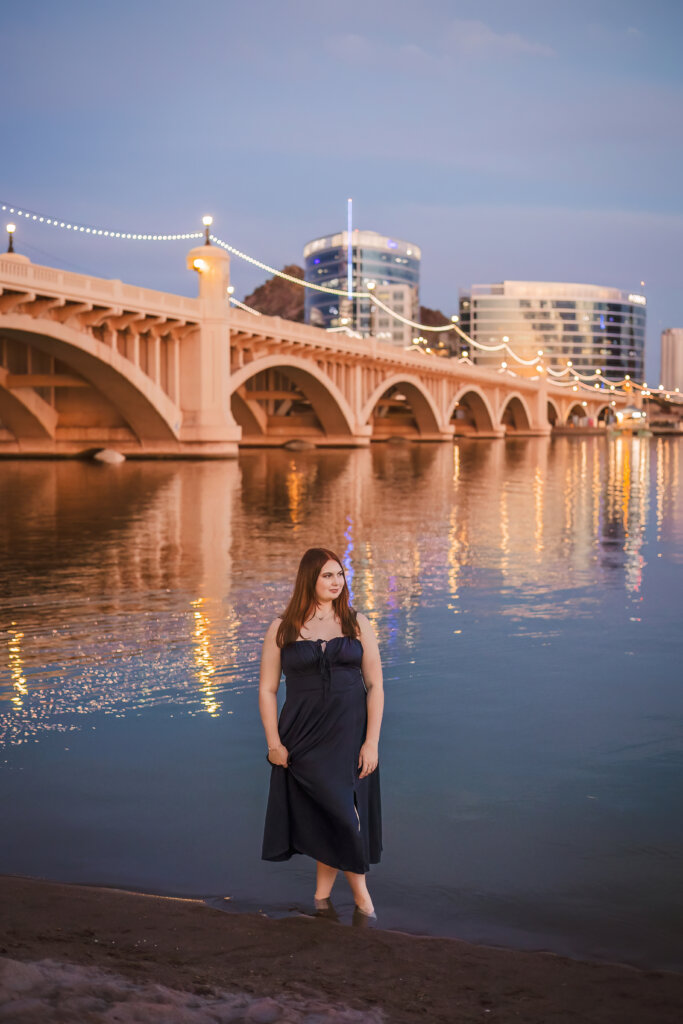 Phoenix senior photographer captures ASU Prep High School student at Tempe Lake with lights reflecting on the water and bridge in the background.