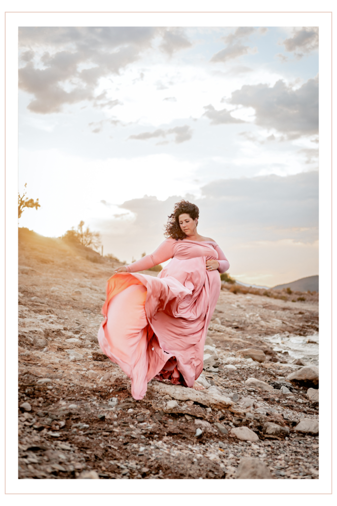 Wind blown dress and hair of pregnant woman during maternity photoshoot near Lake Pleasant, captured by Phoenix photographer.